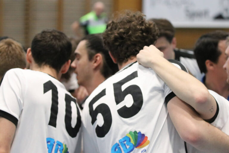 Eine Gruppe Männer in schwarz-weissen Trikots drängt sich zusammen.