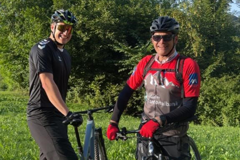 Zwei Mountainbiker stehen nebeneinander auf einem Feld.