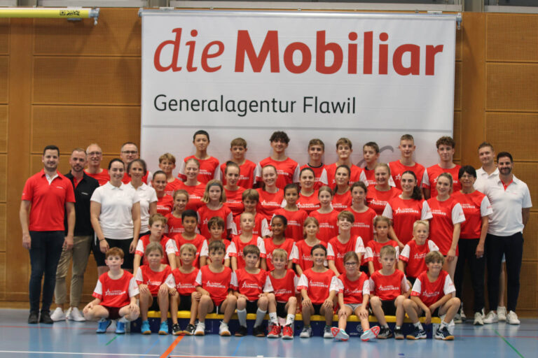 Eine Gruppe von Menschen posiert mit roten T-Shirts vor dem "die Mobiliar"-Banner.