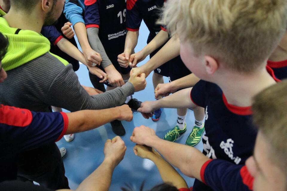 Eine Gruppe von Handballspielern im Kreis, strecken ihre Fäuste in die Mitte.